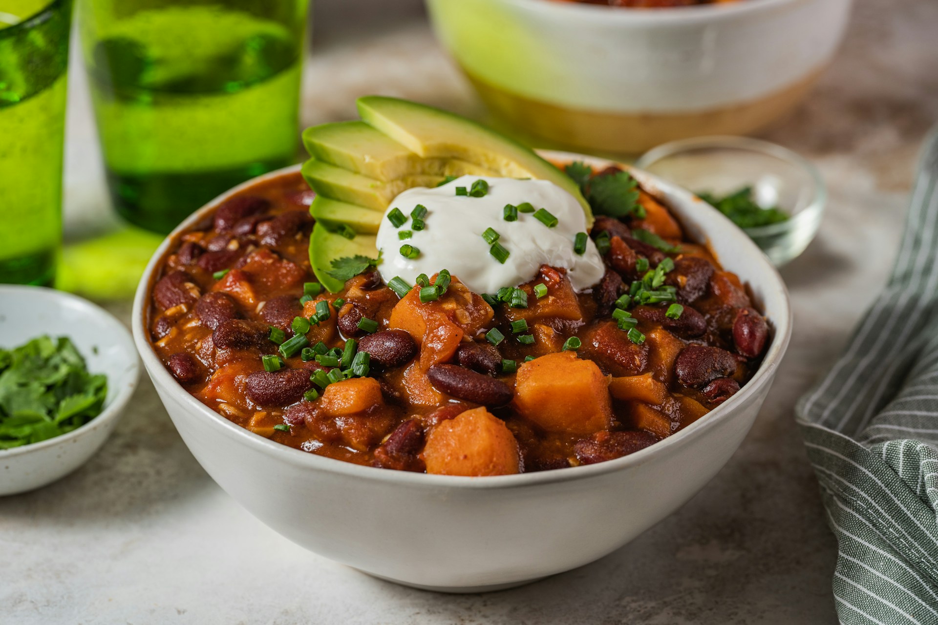 Klasyczne chili con carne podane w białej misce z dodatkiem śmietany i awokado