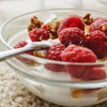Jogurt z malinami i orzechami w szklanej miseczce